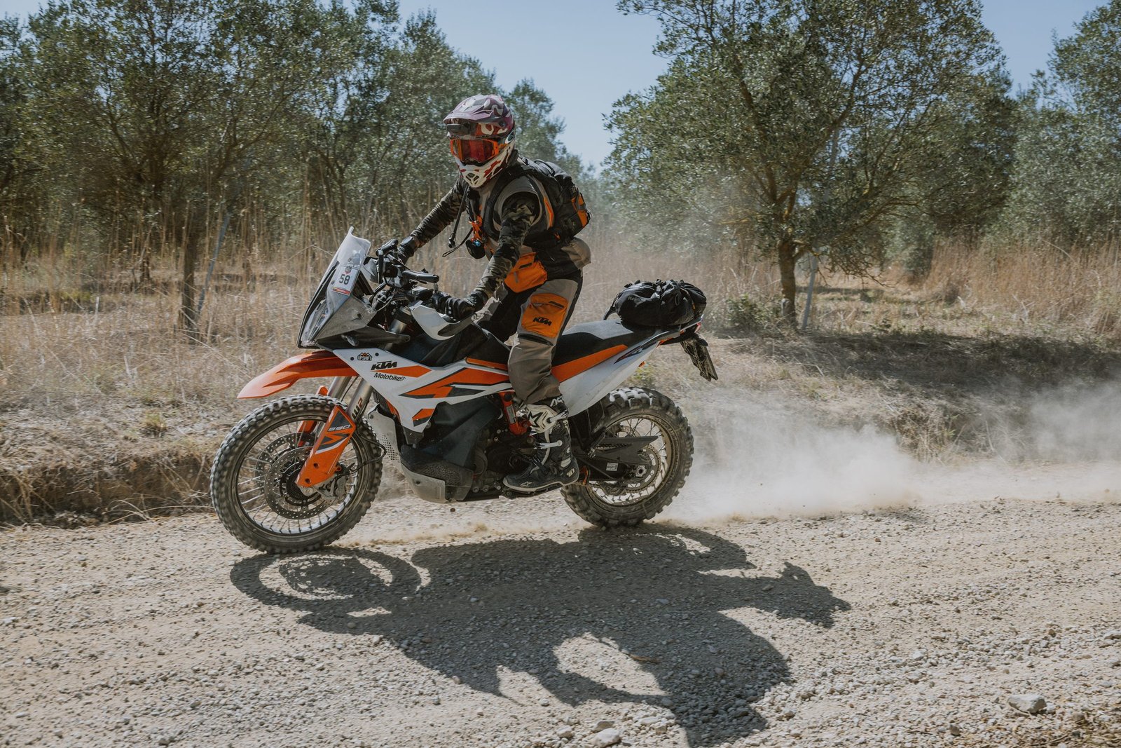 KTM rider kicking up dust through an olive grove on Day 2, Umbria