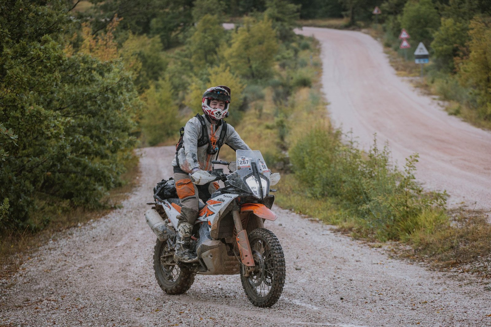 KTM rider on a white gravel road through the forest, Umbria