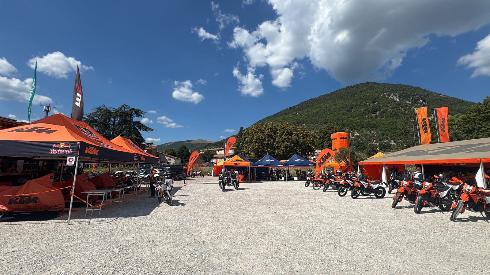 KTM Adventure Rally Italy 2026 paddock of orange tents below the hills of Gubbio, Umbria