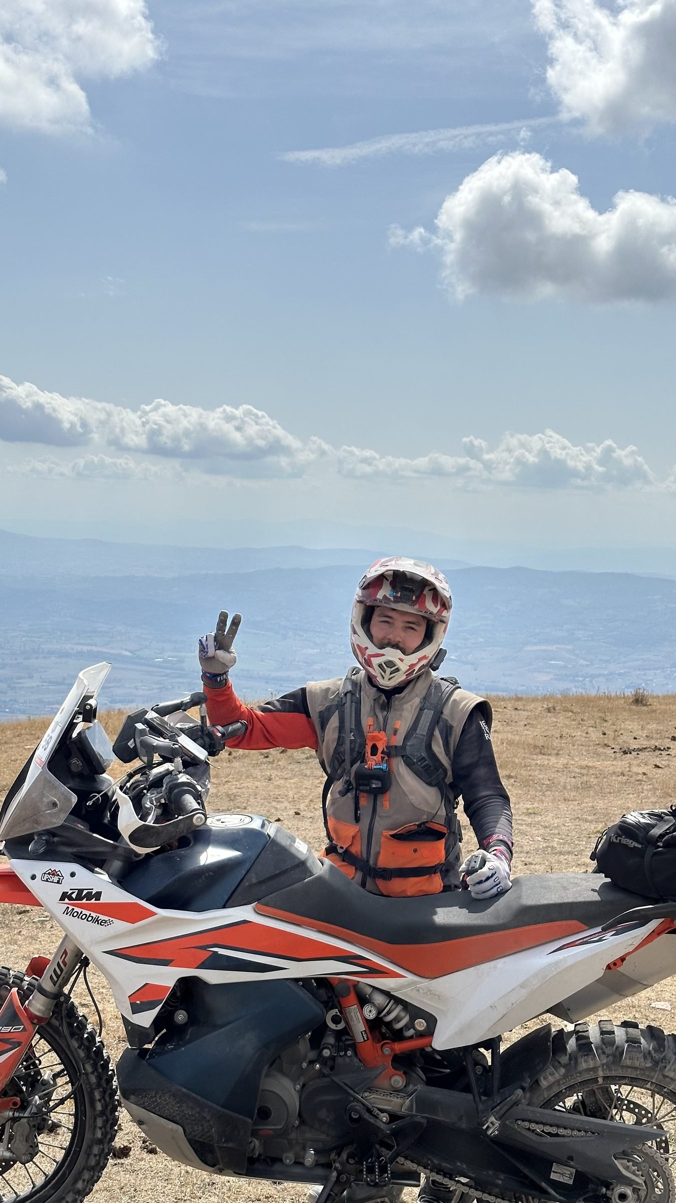 Rider with a peace sign next to the KTM on an Apennine hilltop
