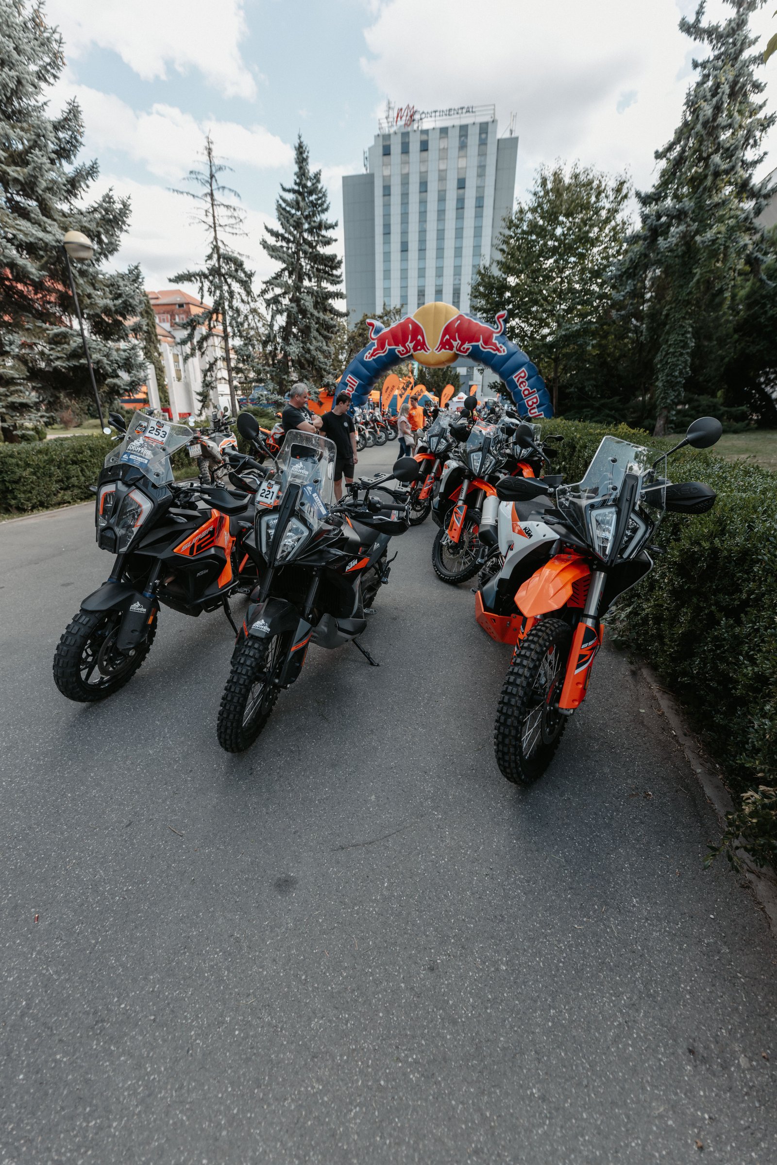 KTM bikes lined up under the Red Bull arch at the rally start