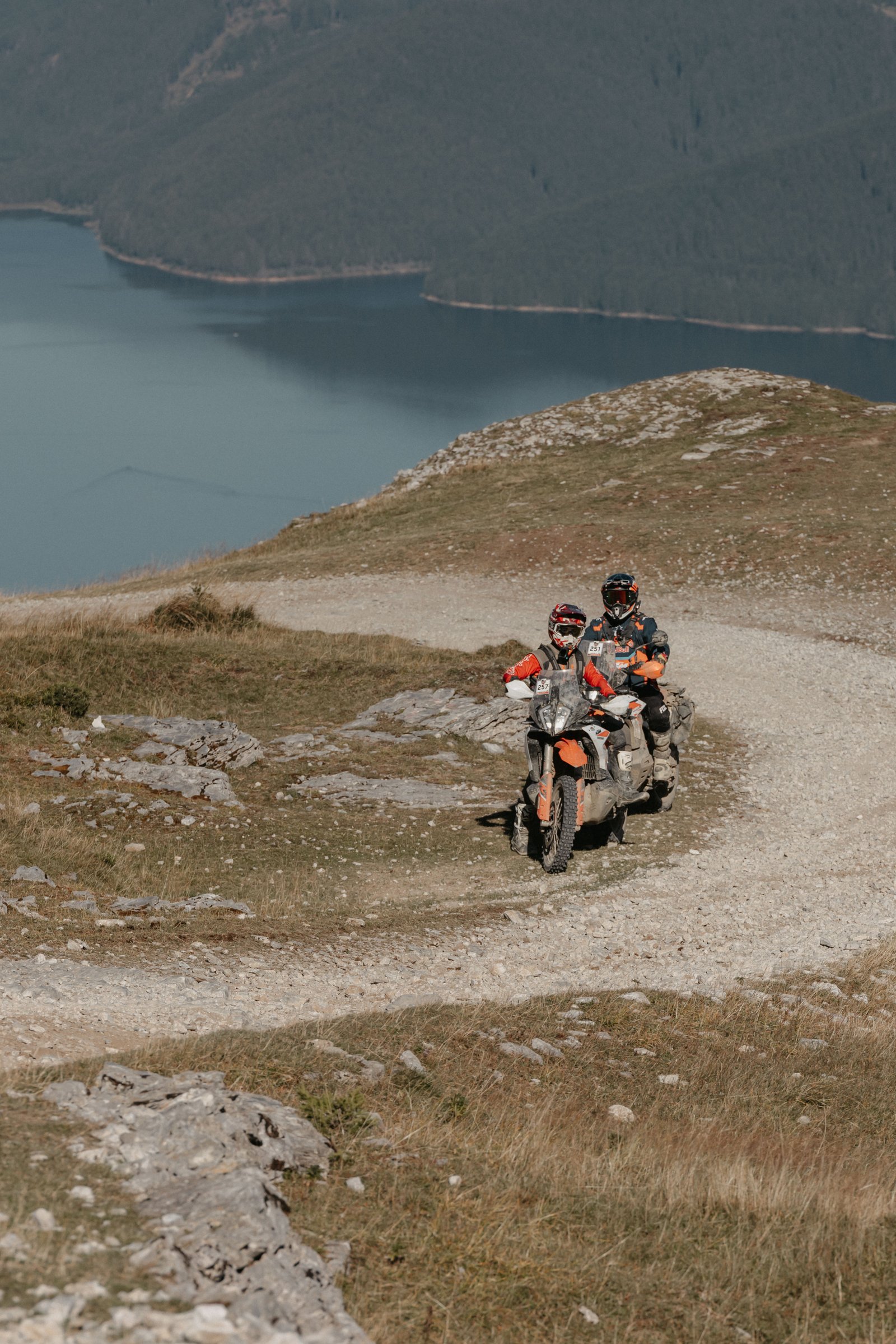 Riders on a mountain path with a lake view in the background