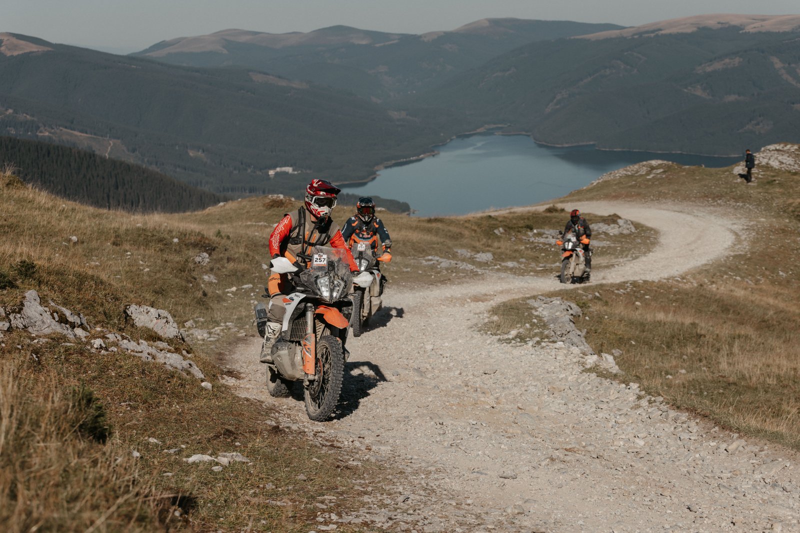 Riders on a rocky trail with a lake far below