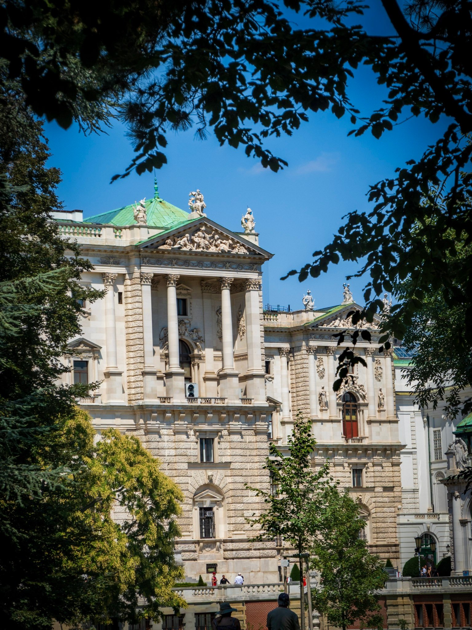 Hofburg Palace facade seen through garden trees, Vienna Austria