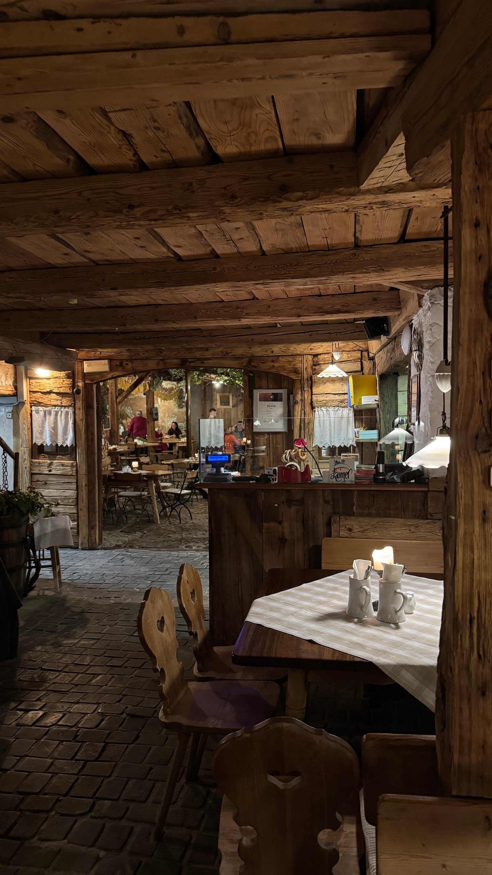 Pfefferlechner Lana restaurant interior with wooden beams and candlelit tables, South Tyrol